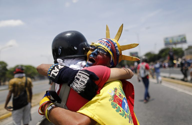 AP Photo,Un manifestante antigubernamental disfrazado de Lady Liberty con los colores de la bandera venezolana, abraza a otro durante una protesta cerca de la base áerea militar de La Carolina, en Caracas, Venezuela, el 1 de mayo de 2019. (AP Foto/Ariana Cubillos)
