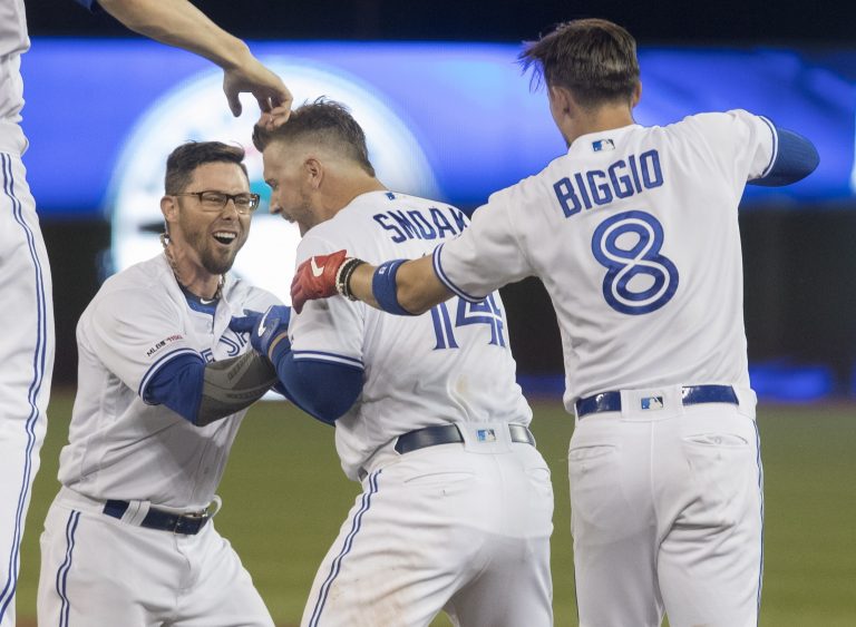 AP Photo,El jugador de los Azulejos de Toronto, Justin Smoak (14), celebra con sus compañeros Eric Sogard y el receptor Cavan Biggio (8), luego de conectar el sencillo productor de la carrera ganadora durante el 10mo inning de un juego de béisbol contra los Indios de Cleveland, el martes 23 de julio de 2019, en Toronto. (Fred Thornhill/Canadian Press vía AP)