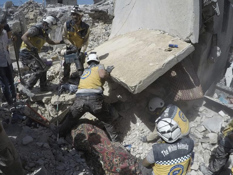 AP Photo,Esta foto proporcionada por la Defensa Civil Siria, conocida como los Cascos Blancos, que ha sido autentificada en base a su contenido y reporteo de AP, muestra a socorristas Cascos Blancos buscando a víctimas debajo de escombros de un edificio destruido por un bombardeo del gobierno sirio, en el pueblo de Ariha, en la provincia de Idlib, Siria, el viernes 12 de julio del 2019. (Cascos Blancos via AP)
