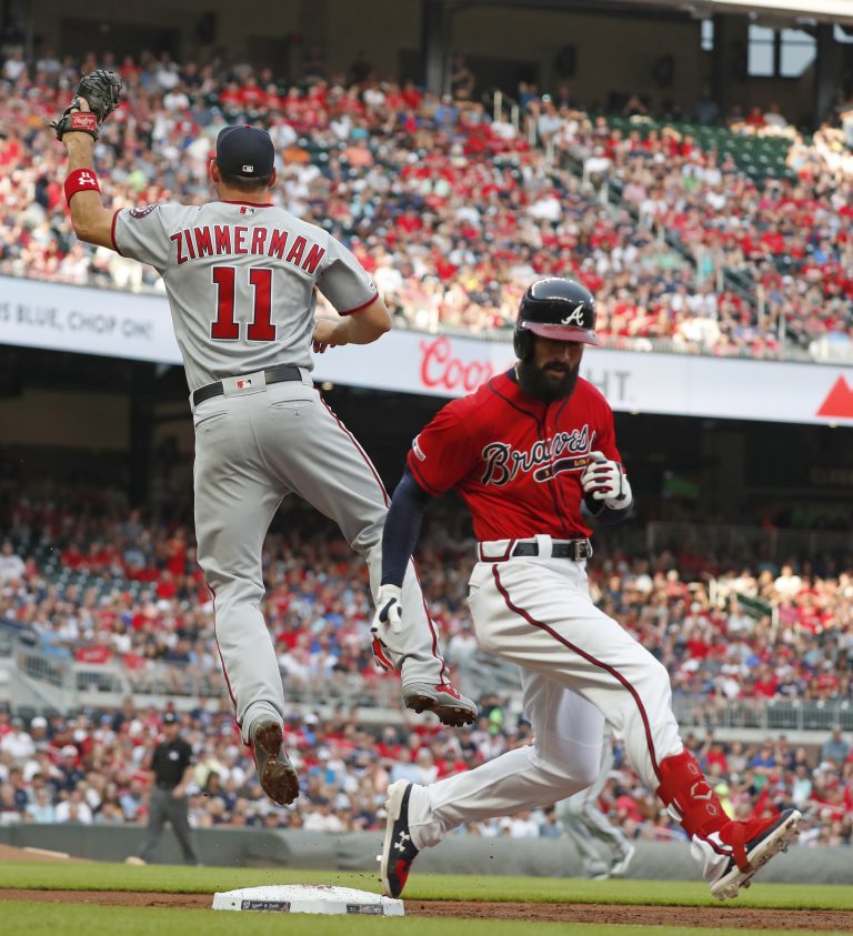 AP Photo, Nick Markakis, Ryan Zimmerman,ARCHIVO - En esta foto de archivo del viernes 19 de julio de 2019, el primera base de los Nacionales de Washington, Ryan Zimmerman (11), salta para atrapar la pelota mientras el jugador de los Bravos de Atlanta, Nick Markakis, llega safe durante el primer inning de un juego de béisbol, en Atlanta. (AP Foto/John Bazemore)