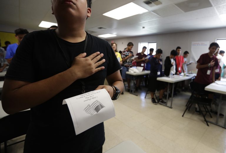 AP Photo,En esta foto del 9 de julio de 2019, inmigrantes juran lealtad a la bandera de Estados Unidos en las instalaciones para niños migrantes de Carrizo Spring, Texas. (AP Foto/Eric Gay)