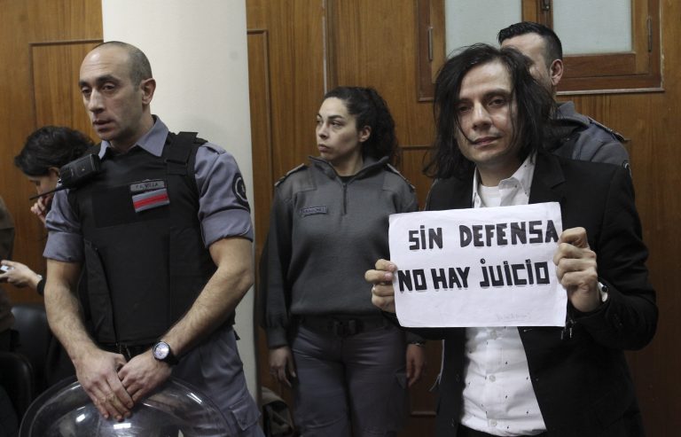 AP Photo,Cristian Aldana, vocalista principal de la banda de rock argentina El Otro Yo, posa durante su juicio por presunto abuso sexual de menores con un cartel que dice 